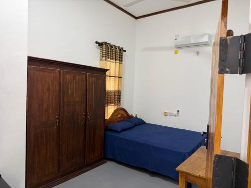 a bedroom with a bed and a wooden cabinet at Stay Home Arugambay in Arugam Bay