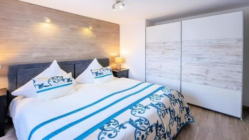 a bedroom with a white bed with blue and white pillows at Apartment Seeterrasse in Schalkenmehren