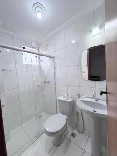 a white bathroom with a toilet and a sink at Palace Hotel Pôr do Sol in Vitória da Conquista
