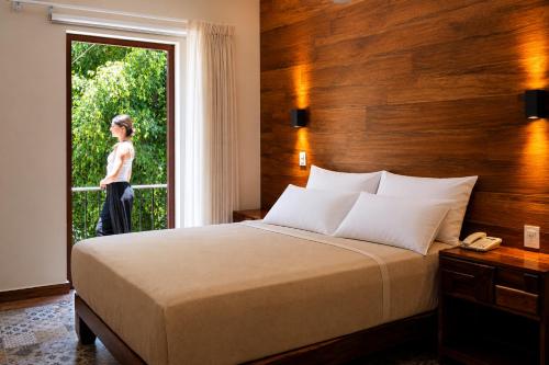 a woman standing outside a bedroom window with a bed at Gran Vila Nai Boutique Hotel in Guadalajara