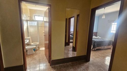 a bathroom with a toilet and a sink and a mirror at Hotel Avenida in General Alvear