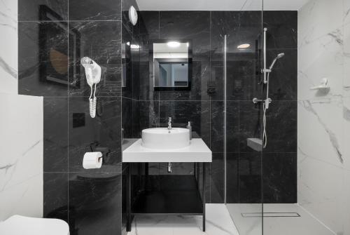 a black and white bathroom with a sink and a shower at Solny Resort Apartament A245 in Kołobrzeg