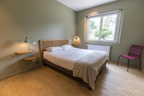 a bedroom with a bed and a window and a chair at Petite villa cassora in Herm