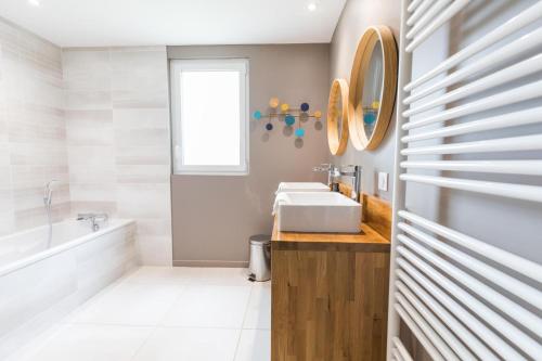 a bathroom with a sink and a tub and a mirror at Petite villa cassora in Herm