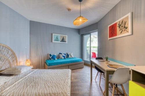a bedroom with a bed and a desk and a table at Le Murmure des palmiers in La Grande Motte