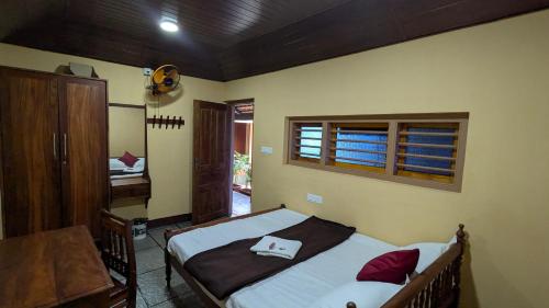a bedroom with a bed and a table and a window at Kabani Villa in Mananthavady