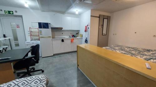 a room with a bed and a desk and a kitchen at Cozy studio apartment with 2 beds and kitchen in Audun-le-Tiche
