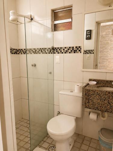 a bathroom with a toilet and a glass shower at Hotel Pousada Casuarinas in Recife