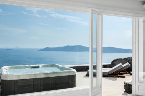 a hot tub on a patio with a view of the ocean at Neraé Santorini in Imerovigli
