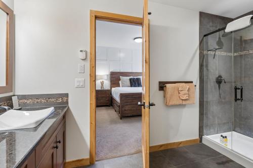 a bathroom with a sink and a shower and a bed at Rundle Cliffs Lodge by Canmore Premier in Canmore