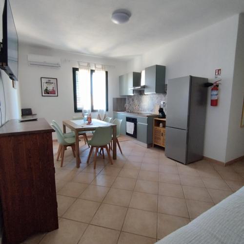 a kitchen and dining room with a table and a refrigerator at Pauli's apartment in Valledoria