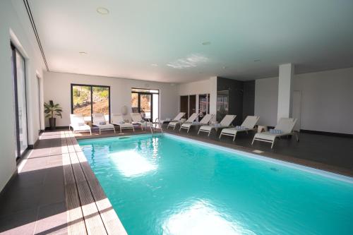 a large swimming pool with white chairs in a building at Hotel Freixo Douro Superior in Freixo de Espada à Cinta