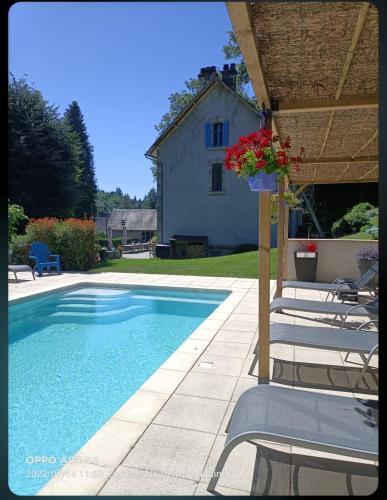 a swimming pool with chairs and a house in the background at Ted et Breakfast in Corrèze