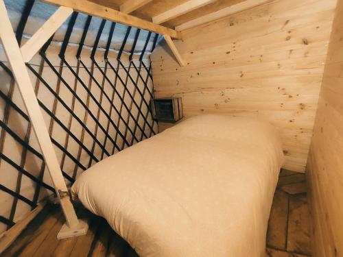 a small room with a bed in a wooden cabin at Au Clères de yourte in Cléres