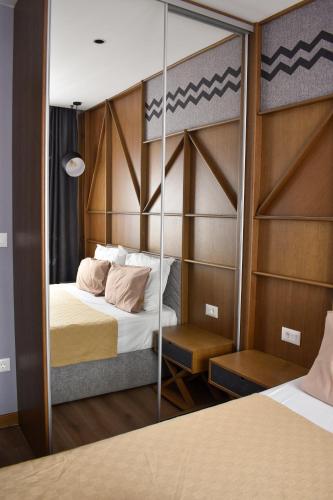 a bedroom with a bed with a mirror on the wall at Zlatibor Lux Spa Apartments in Zlatibor