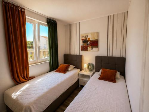 two beds in a room with a window at Apartmani Sollei in Petrcane