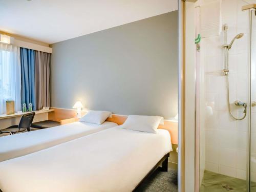 a hotel room with two beds and a shower at Ibis Częstochowa in Częstochowa
