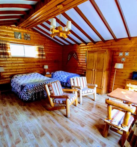 a bedroom with two beds and chairs in a cabin at Kan-à-Mouche Pourvoirie Auberge et Chalets in Saint-Michel-des-Saints