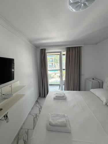a white bedroom with a bed with two towels on it at Elois Apartments in Shëngjin