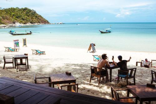 two people sitting at a table on the beach at Sand in My Shoes Beach Loft in Thong Nai Pan Noi