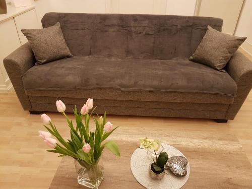 ein Wohnzimmer mit einem Sofa und einem Tisch mit Blumen in der Unterkunft City Apartment in Düren - Eifel