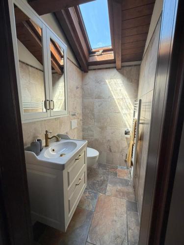 a bathroom with a sink and a toilet and a window at Rustico Villa Antonia with seaview and pool in Bieno