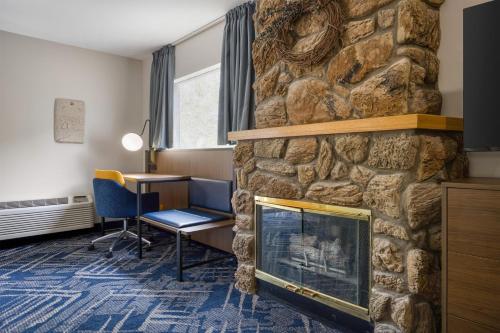 a living room with a stone fireplace and a desk at Best Western Indian Oak in Chesterton