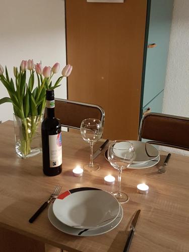 City Apartment في دورين - إيفل: طاولة مع زجاجة من النبيذ وأطباق واكواب