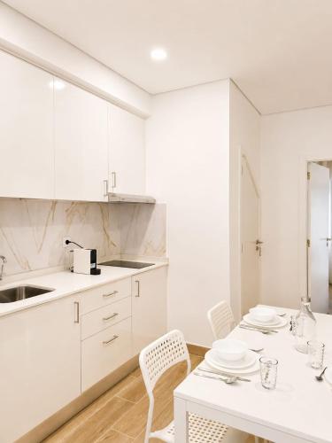 a kitchen with white cabinets and a table and chairs at Casa Rabiosa in Nazaré