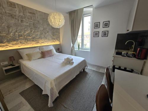 a bedroom with a white bed with a stone wall at Studio Apartments - Pula city center in Pula