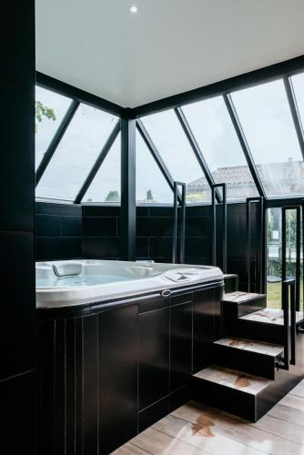 a bathroom with a bath tub and some windows at Hostellerie Saint-Louis & Restaurant Pauze - Teritoria in Bollezeele