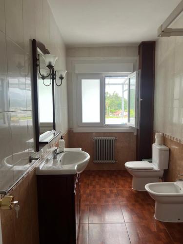 a bathroom with two sinks and a toilet and a mirror at pensión Palongo in Caldas de Reis
