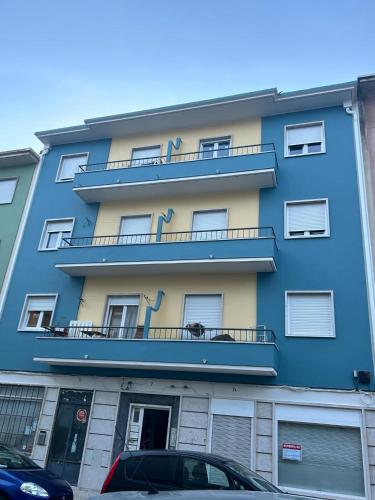 a blue apartment building with a dog on the balcony at Quarto 15 min de Lisboa in Amadora