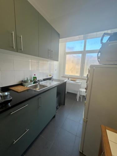 a kitchen with a sink and a refrigerator at Quarto 15 min de Lisboa in Amadora