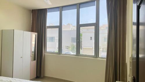 a bedroom with a window and a white refrigerator at Alsayah in Jazīrat as Sāyah