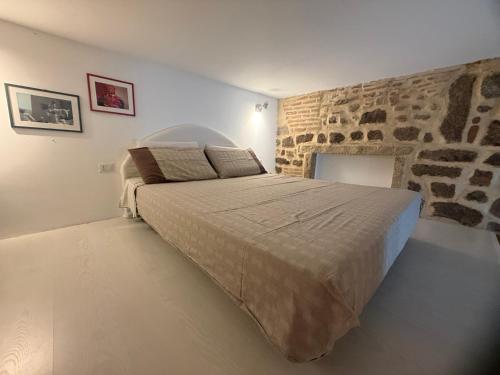 a bedroom with a large bed with a stone wall at Victoria in Olbia
