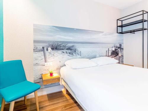 a bedroom with a bed and a blue chair at ibis Styles Quimper in Quimper
