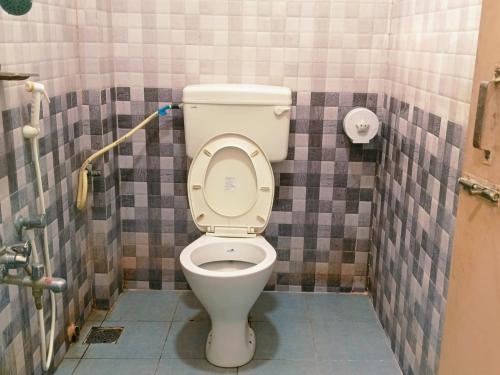 a bathroom with a toilet with a tiled wall at Pacio Residency in Kanchipuram