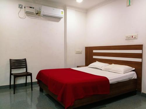 a bedroom with a bed with a red blanket and a chair at Pacio Residency in Kanchipuram