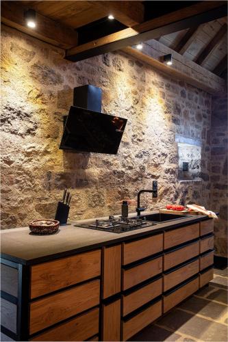 a kitchen with a sink and a stone wall at Buron du Tournel, un écrin d'exception in Le Lioran
