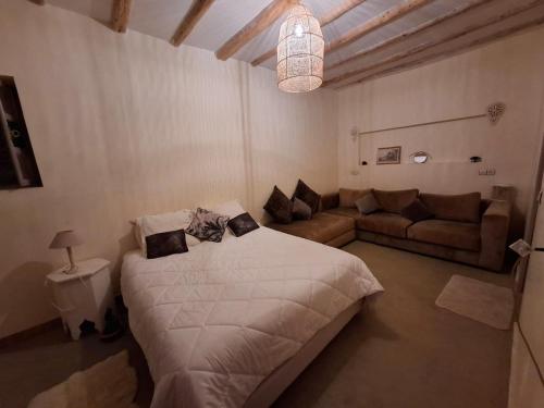 a bedroom with a large bed and a couch at Gîte berbère in Tagadirt Alkadi