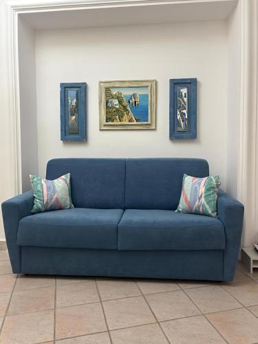 a blue couch in a living room with paintings on the wall at 2Steps Capri - central holiday house in Capri