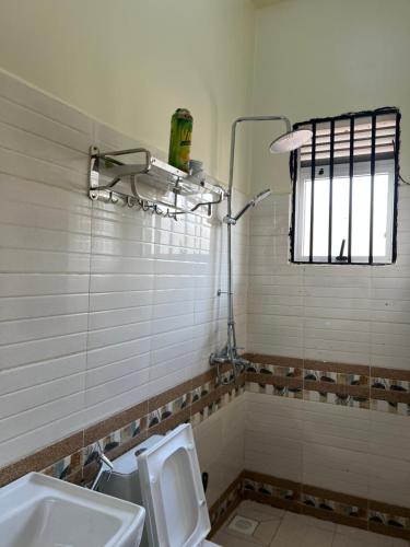 a bathroom with a toilet and a sink and a window at Modern 1BR Apartment with Pool & Sauna Kampala in Kira