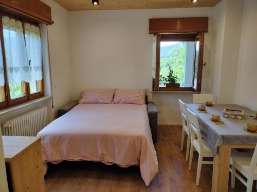 a bedroom with a bed and a table and a window at Casa Silva in Pieve Tesino