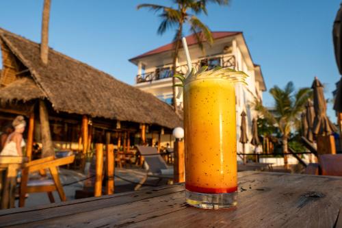 a drink sitting on top of a wooden table at Dhow Beach Boutique Hotel in Nungwi
