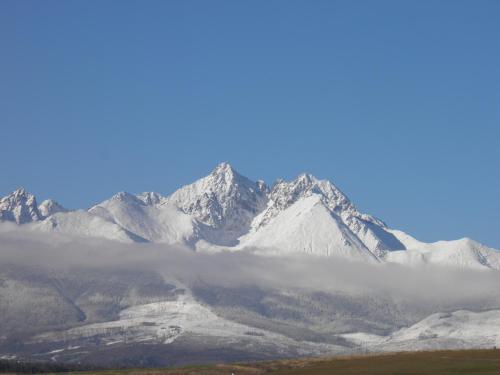 a mountain covered in snow and clouds in front of it at Privát Slavkov in Malý Slavkov