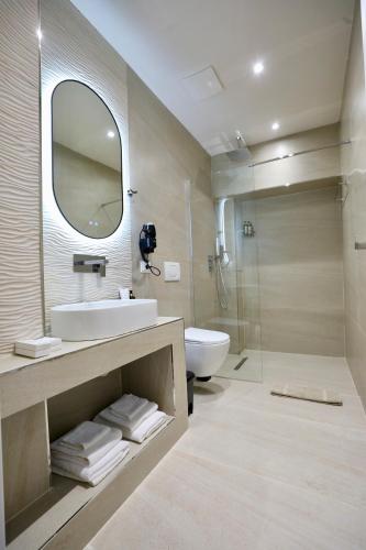a bathroom with a sink and a toilet and a mirror at Andorini Hotel in Finiq