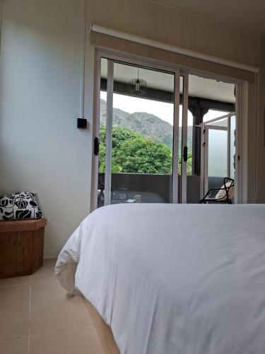 a bedroom with a white bed and a window at Kot Ory Mountain View Studio in Moka