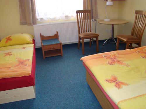 a bedroom with two beds and chairs and a window at Penzion Cabák in Vrchlabí