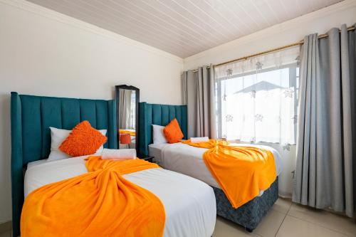 two beds with orange sheets in a room with a window at Safi Elegant Self-catering Suite 5 in East London